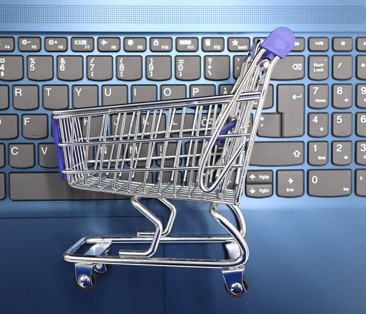 A small shopping cart set on a laptop keyboard, representing online shopping and e-commerce.